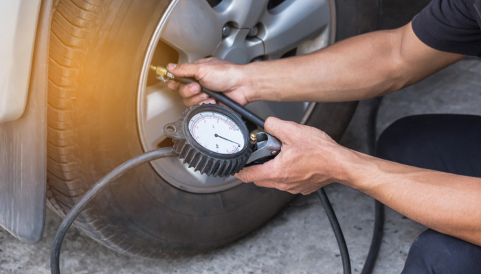 Close up of man inflating a tire and checking air pressure with gauge pressure