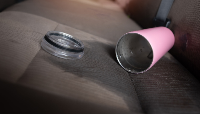 Water spilled from a pink cup on the car backseats