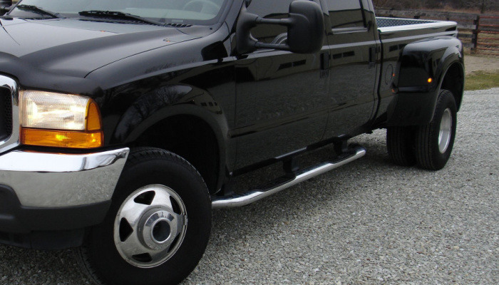Big black dual rear tire diesel pick up truck emephasizing the nerf bars